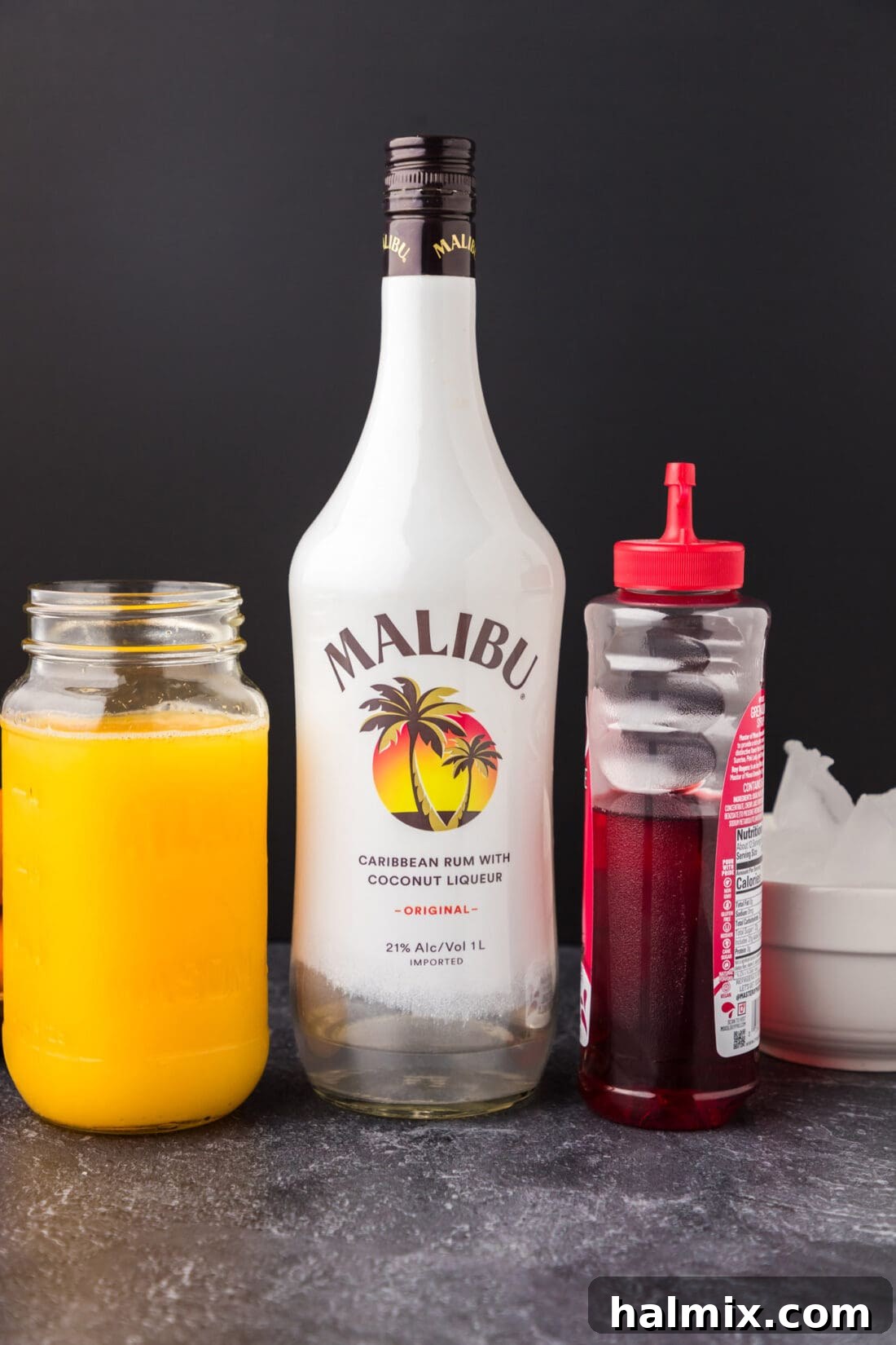 Fresh ingredients for a Malibu Sunrise cocktail, including Malibu rum, orange juice, and grenadine.