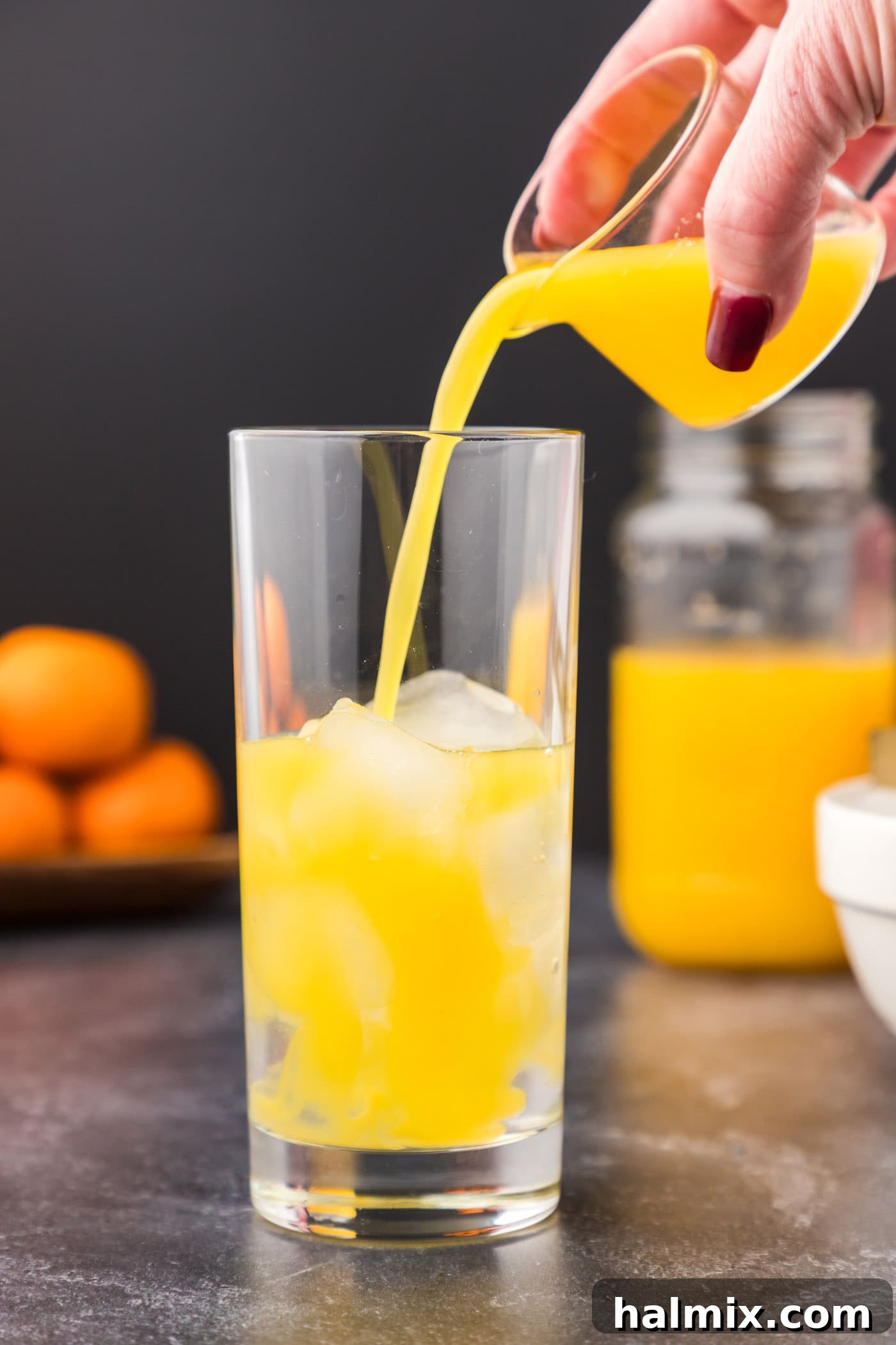 Adding fresh orange juice to a cocktail glass with Malibu rum, creating the base for a Malibu Sunrise.