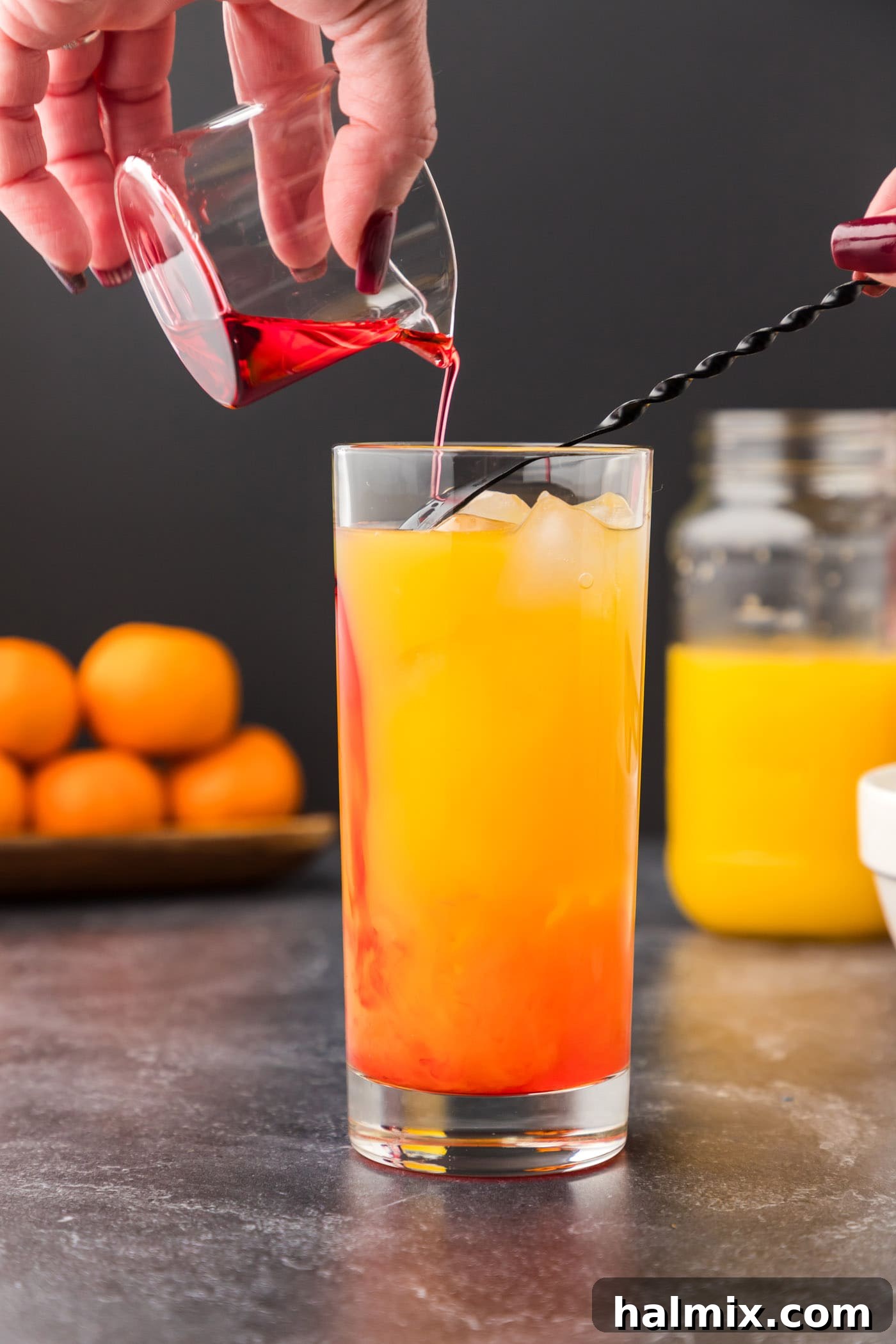 Expertly pouring grenadine over the back of a spoon to create the signature layered effect of a Malibu Sunrise.