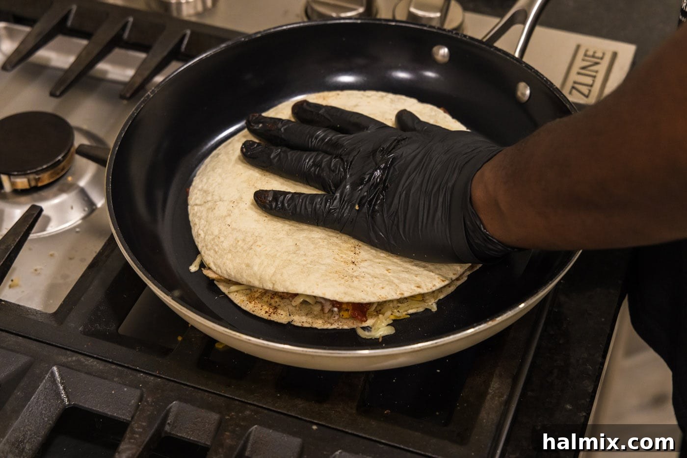 Crispy Ranch Chicken Bacon Quesadillas 15 A hand gently pressing a second tortilla onto the fillings in the skillet to form the quesadilla.