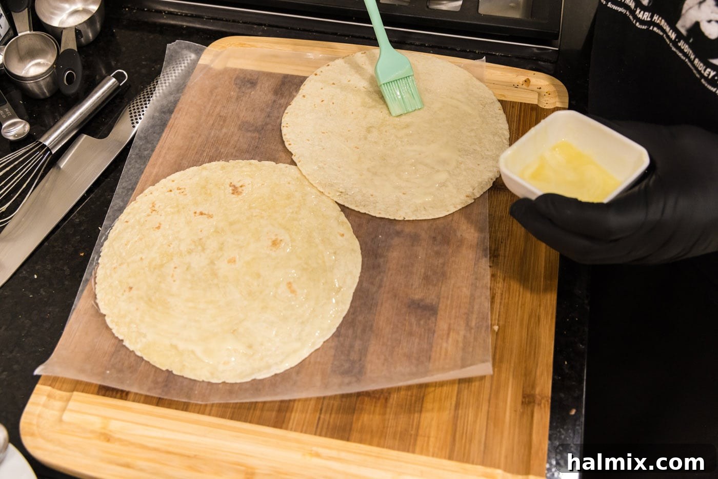 Crispy Ranch Chicken Bacon Quesadillas 5 A tortilla being basted with melted butter on a sheet of wax paper.
