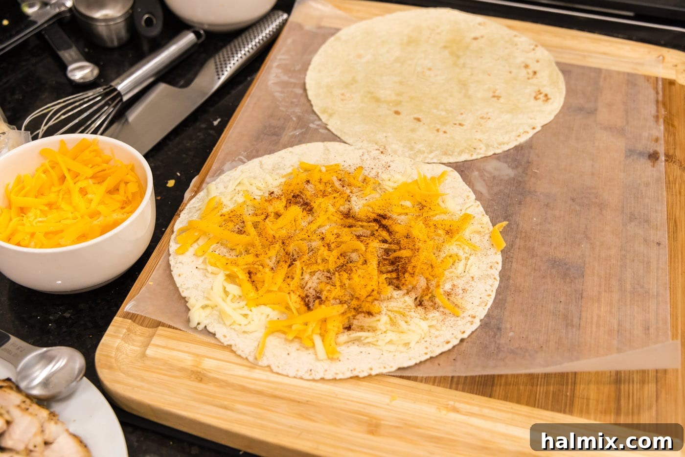Crispy Ranch Chicken Bacon Quesadillas 8 Chili powder being sprinkled over the layer of cheese on the tortilla.
