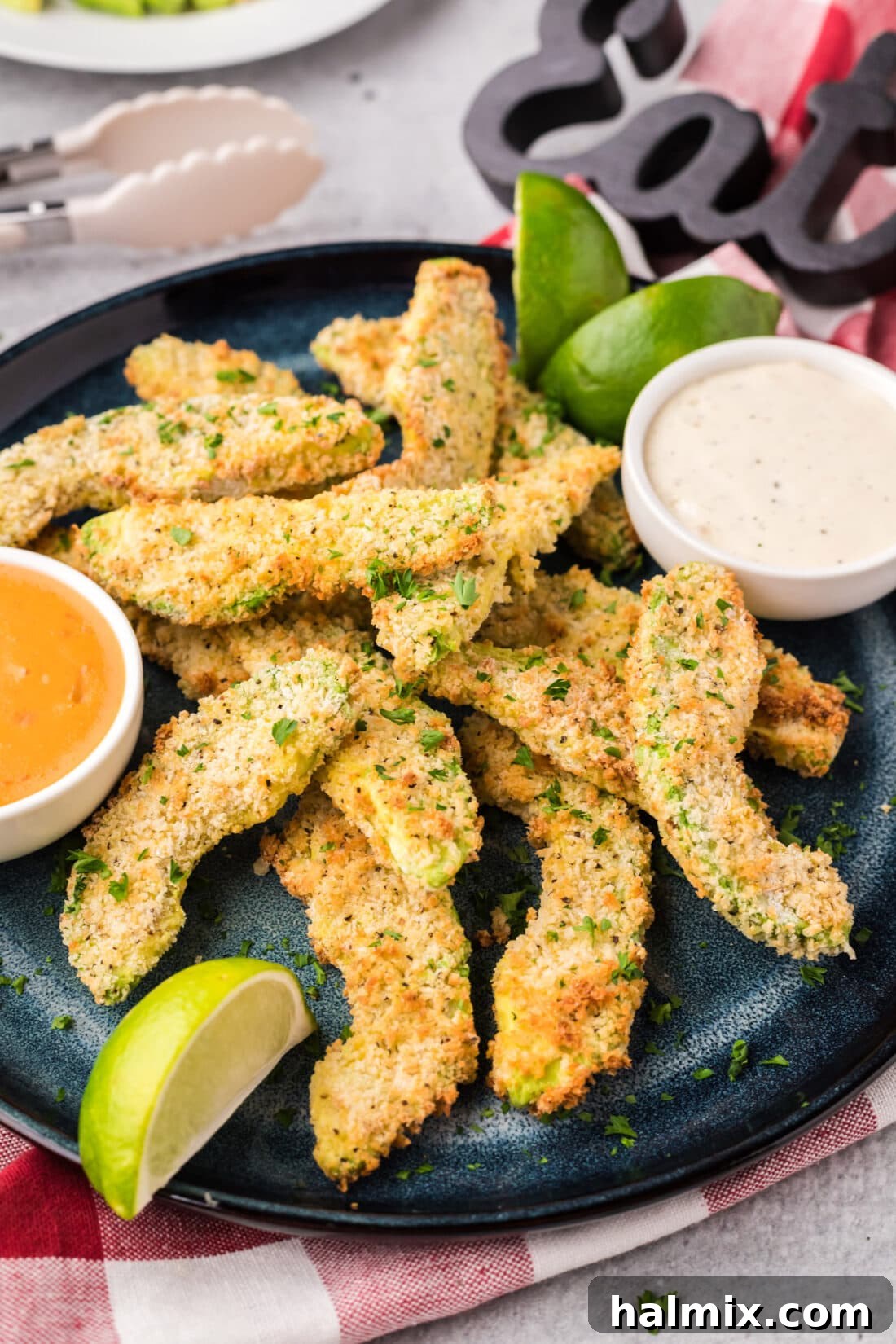 Close up photo of a plate of perfectly golden Air Fryer Avocado Fries, showing their crispy exterior and vibrant green interior.