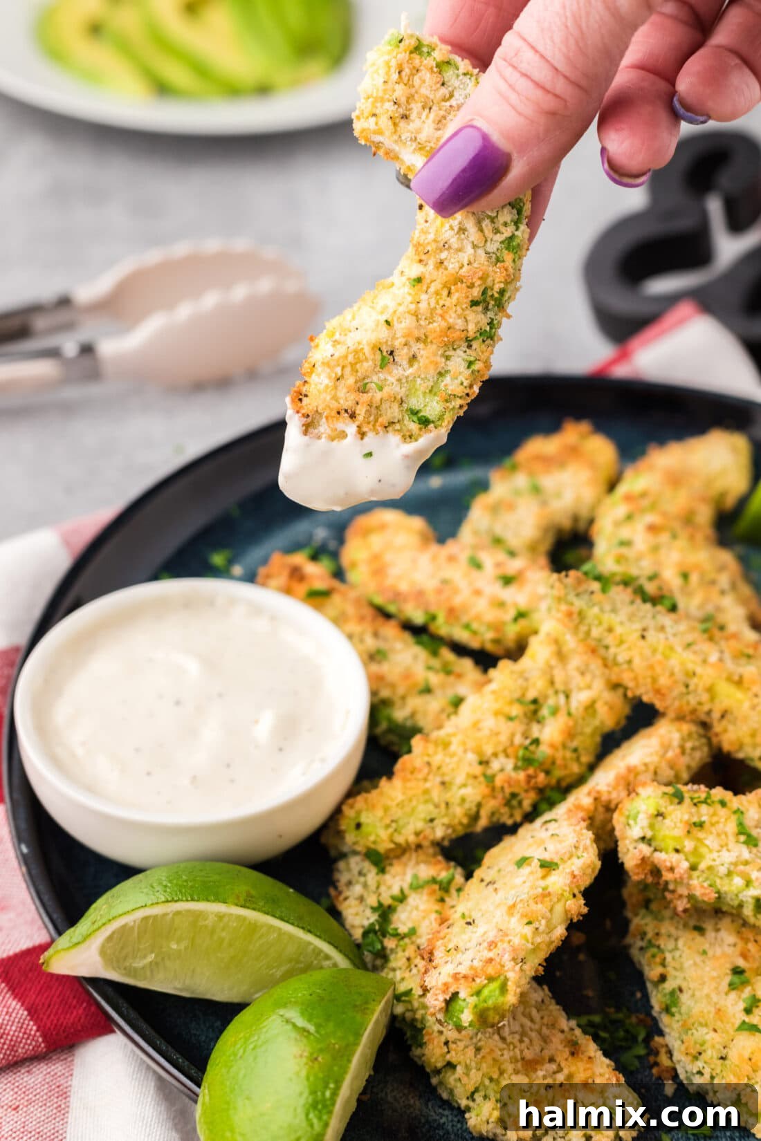 A crispy Air Fryer Avocado Fry being dipped into a creamy ranch sauce.