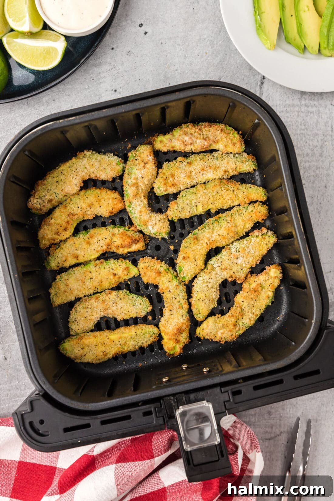 Freshly coated Air Fryer Avocado Fries resting in an air fryer basket, ready for cooking.