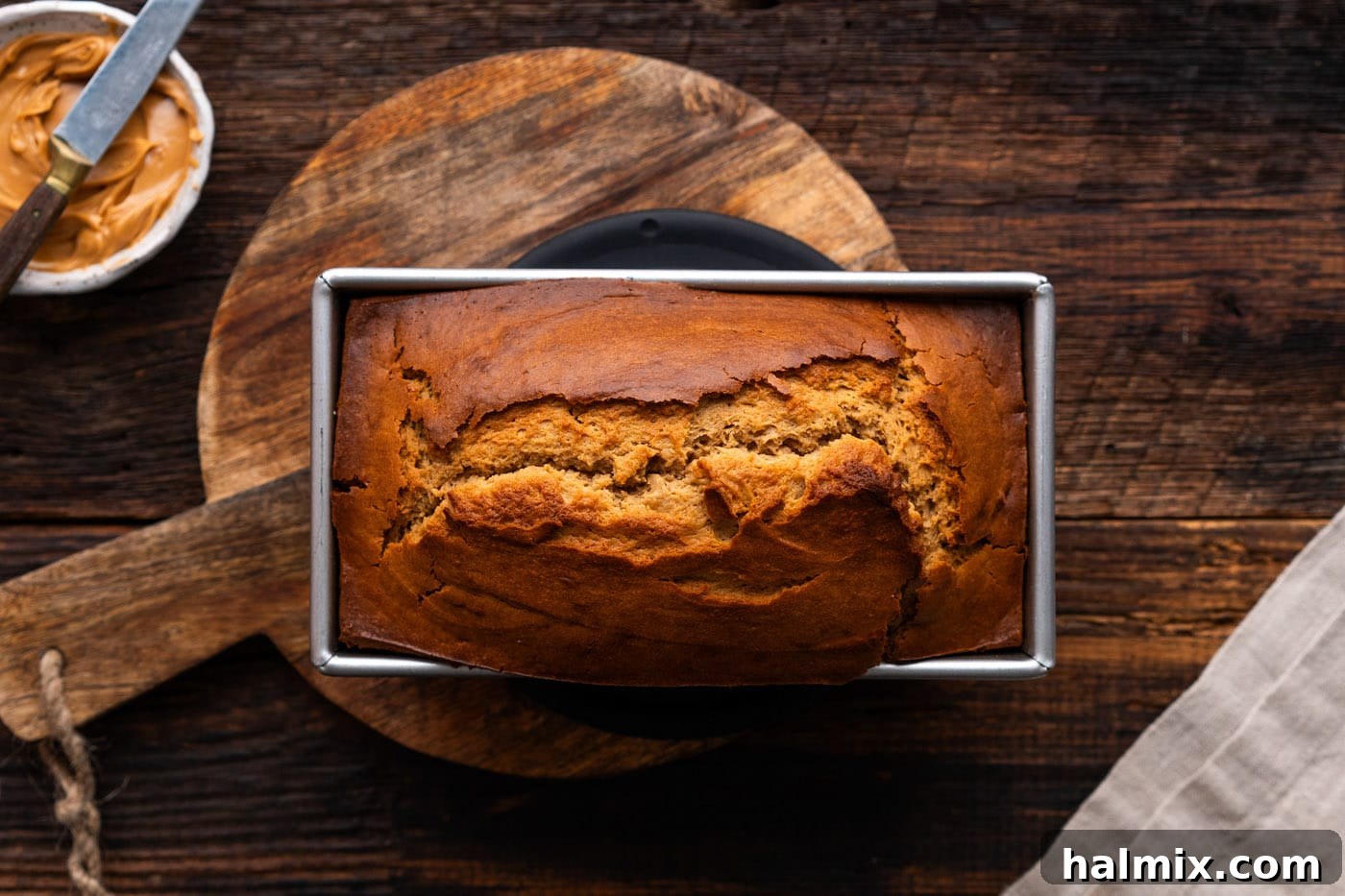 A freshly baked loaf of peanut butter bread, golden brown and still in the loaf pan.