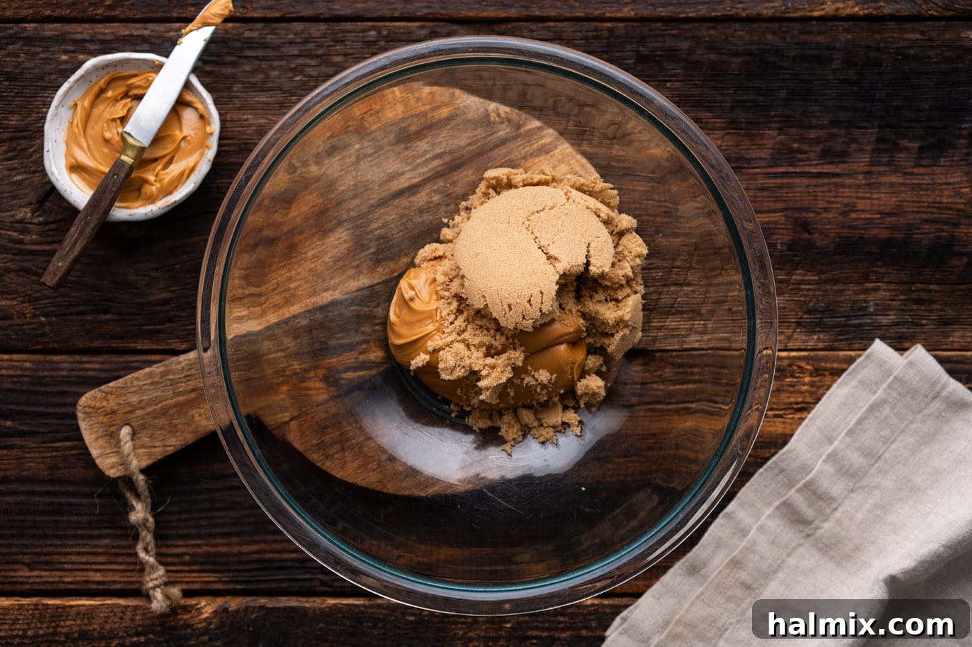 Brown sugar and peanut butter in a mixing bowl being combined with an electric mixer.