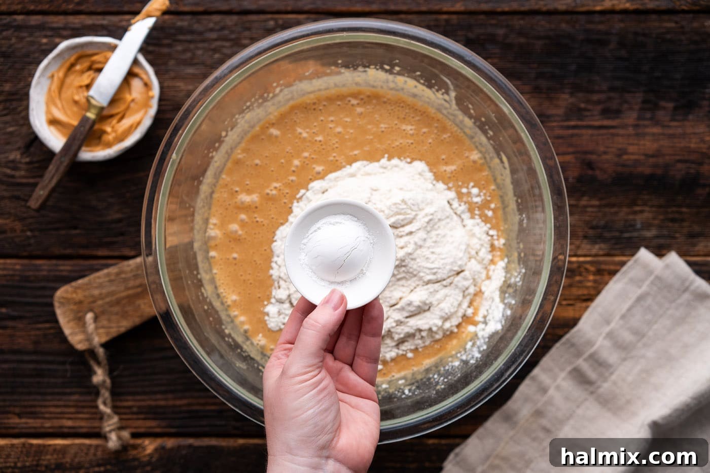 Dry ingredients including flour, baking powder, and salt being added to the peanut butter batter.