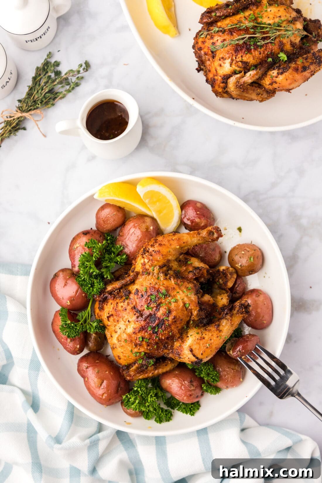 Crispy Air Fryer Cornish Hen served on a bed of roasted potatoes with fresh herbs, ready to eat.