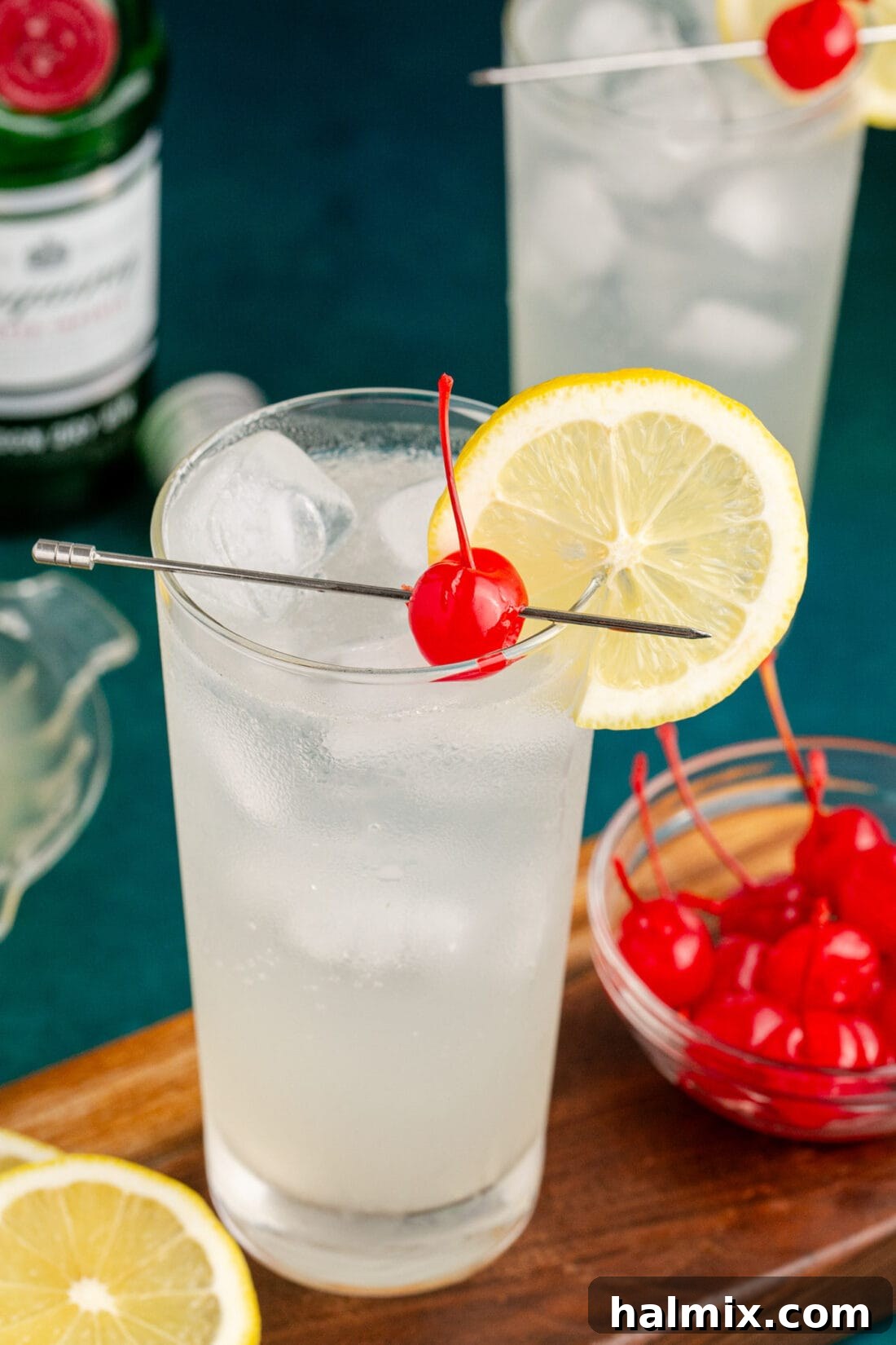 Close up photo of a Tom Collins cocktail garnished with a cherry and lemon wheel