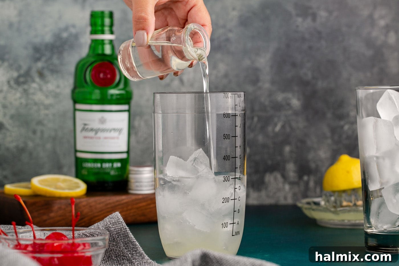 pouring simple syrup over gin and lemon juice