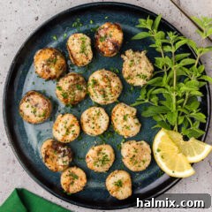 Plate of Grilled Scallops with herbs and lemon slices on the side