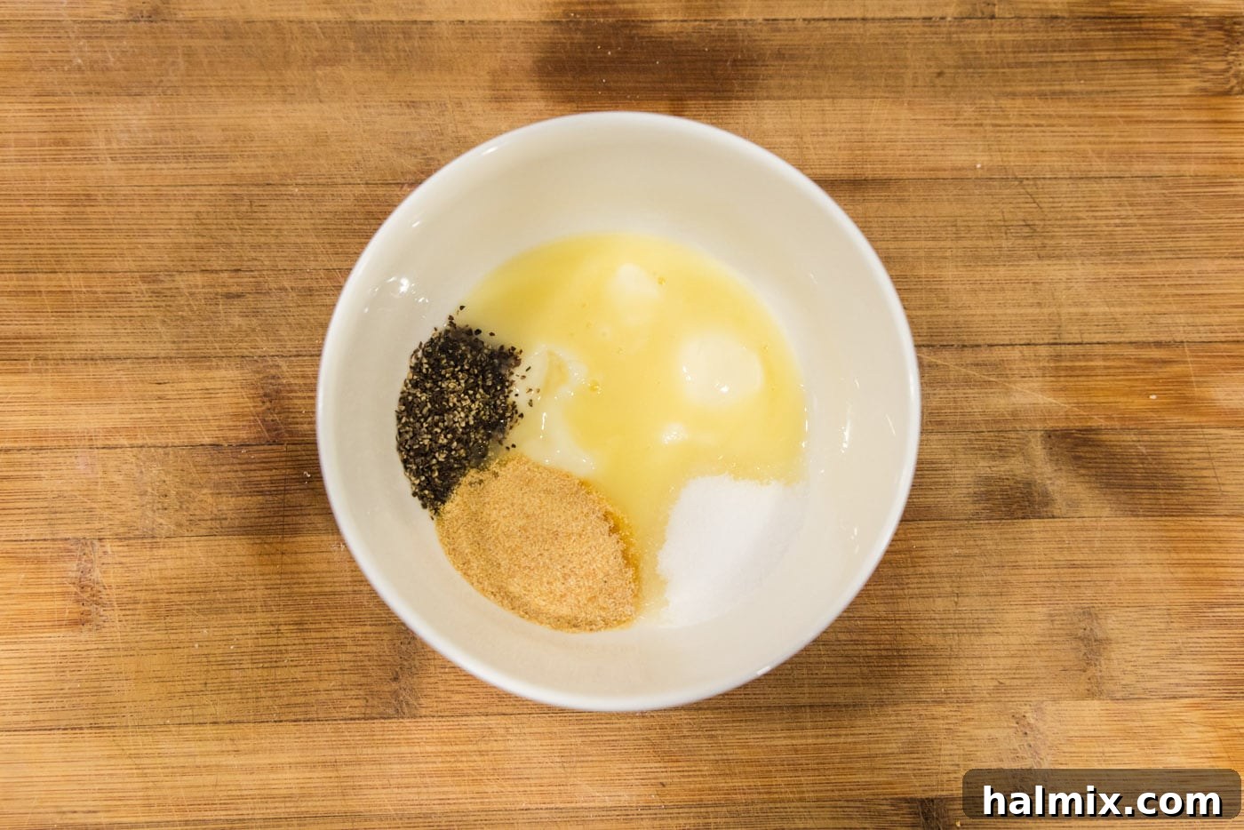 Butter, garlic powder, salt, and pepper in a bowl, ready to be mixed