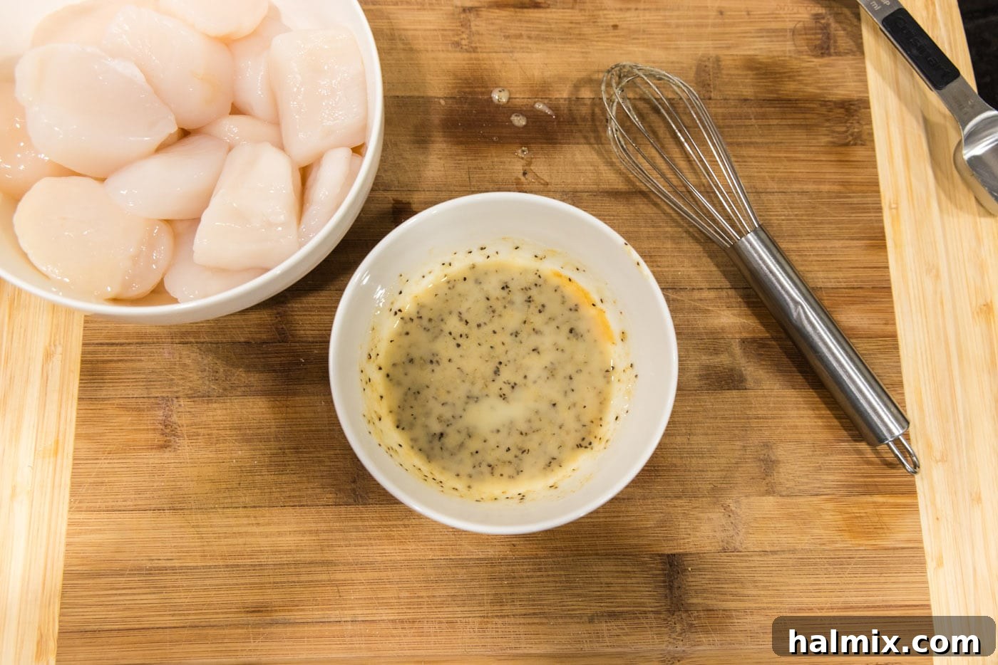 Seasoned butter in a bowl next to a bowl of fresh scallops