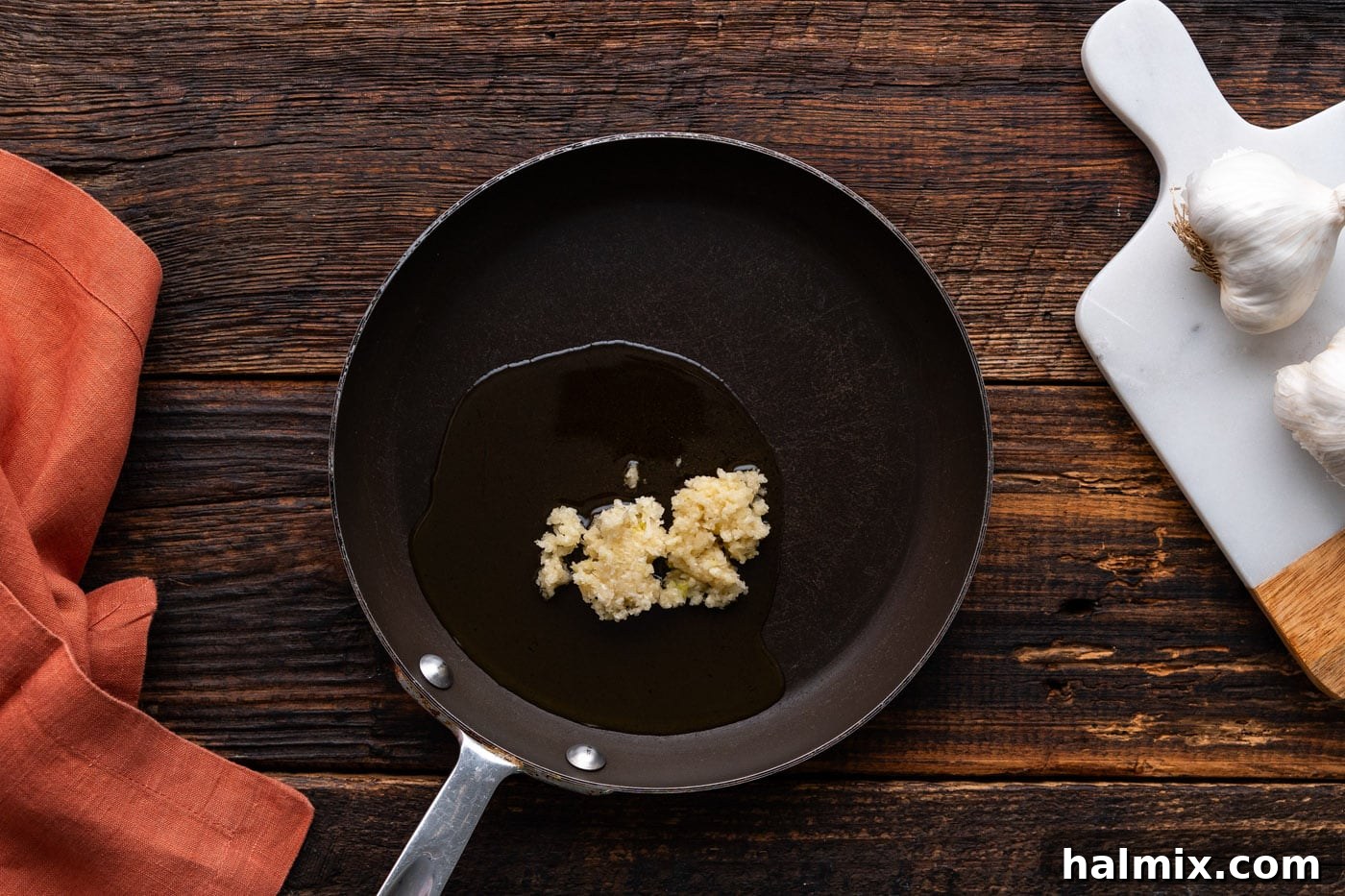 Minced garlic cooking in a small skillet with olive oil