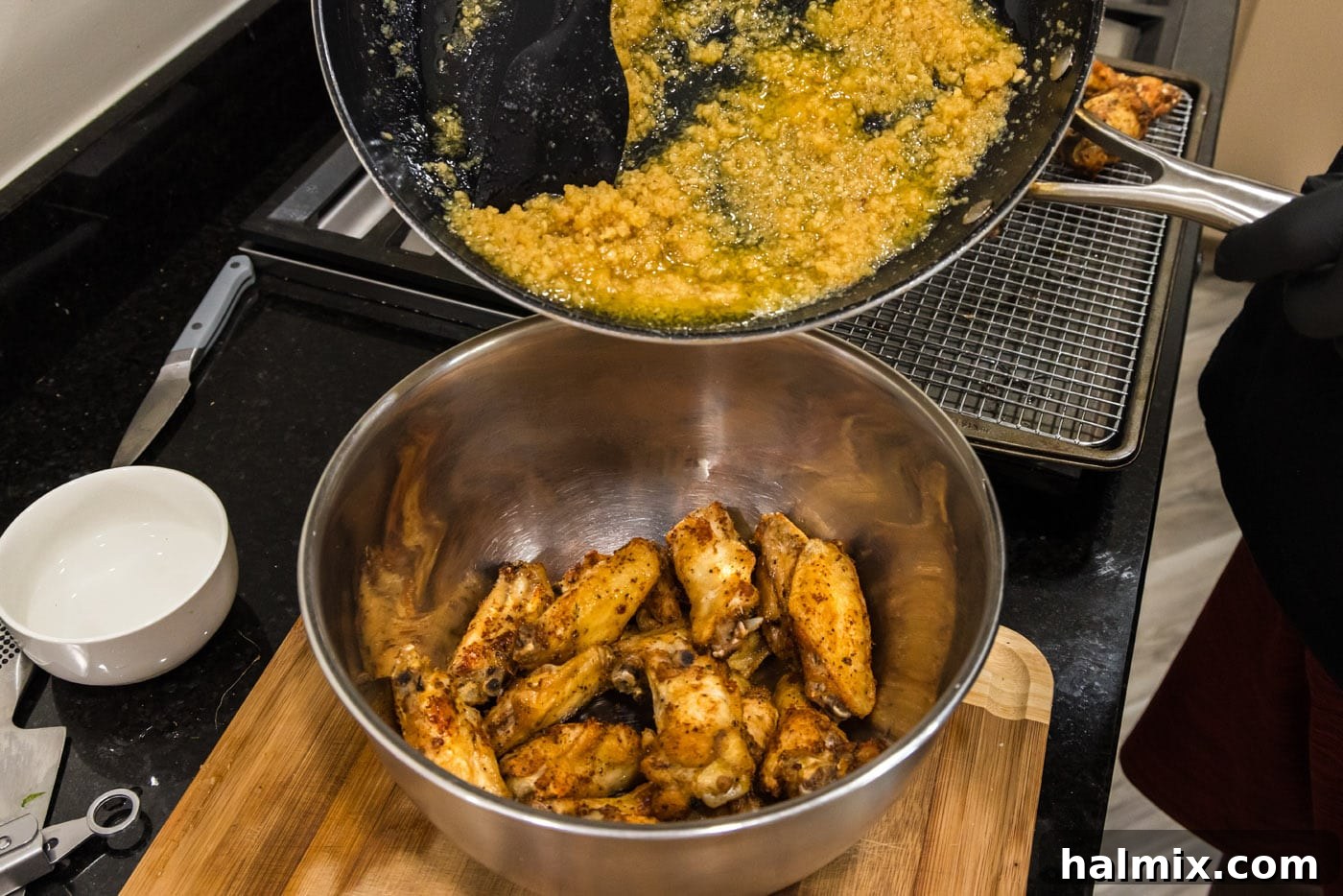 Crispy Garlic Parmesan Wings 15 pouring garlic parmesan sauce over chicken wings in a bowl