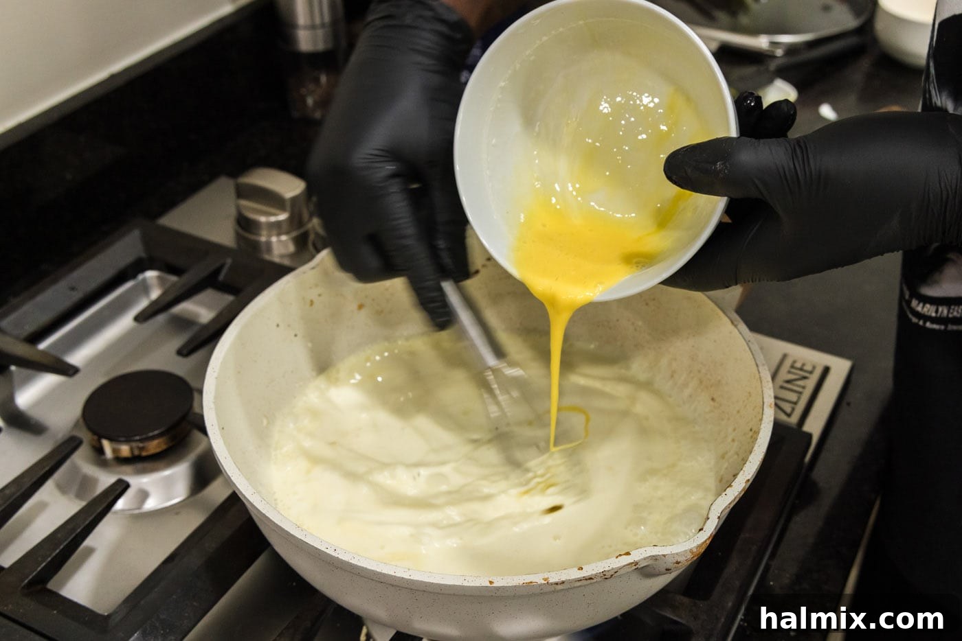 Creamy Chicken and Shrimp Carbonara 12 Slowly pouring whisked eggs into the simmering heavy cream in the skillet while continuously whisking to temper them and prevent scrambling.