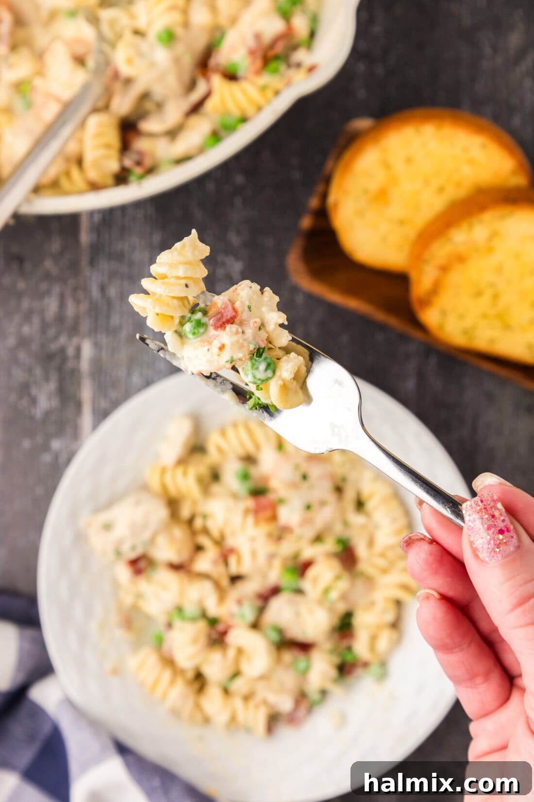Creamy Chicken and Shrimp Carbonara 17 A fork holding a generous swirl of Chicken and Shrimp Carbonara, lifted above a full bowl, highlighting the rich sauce and ingredients.