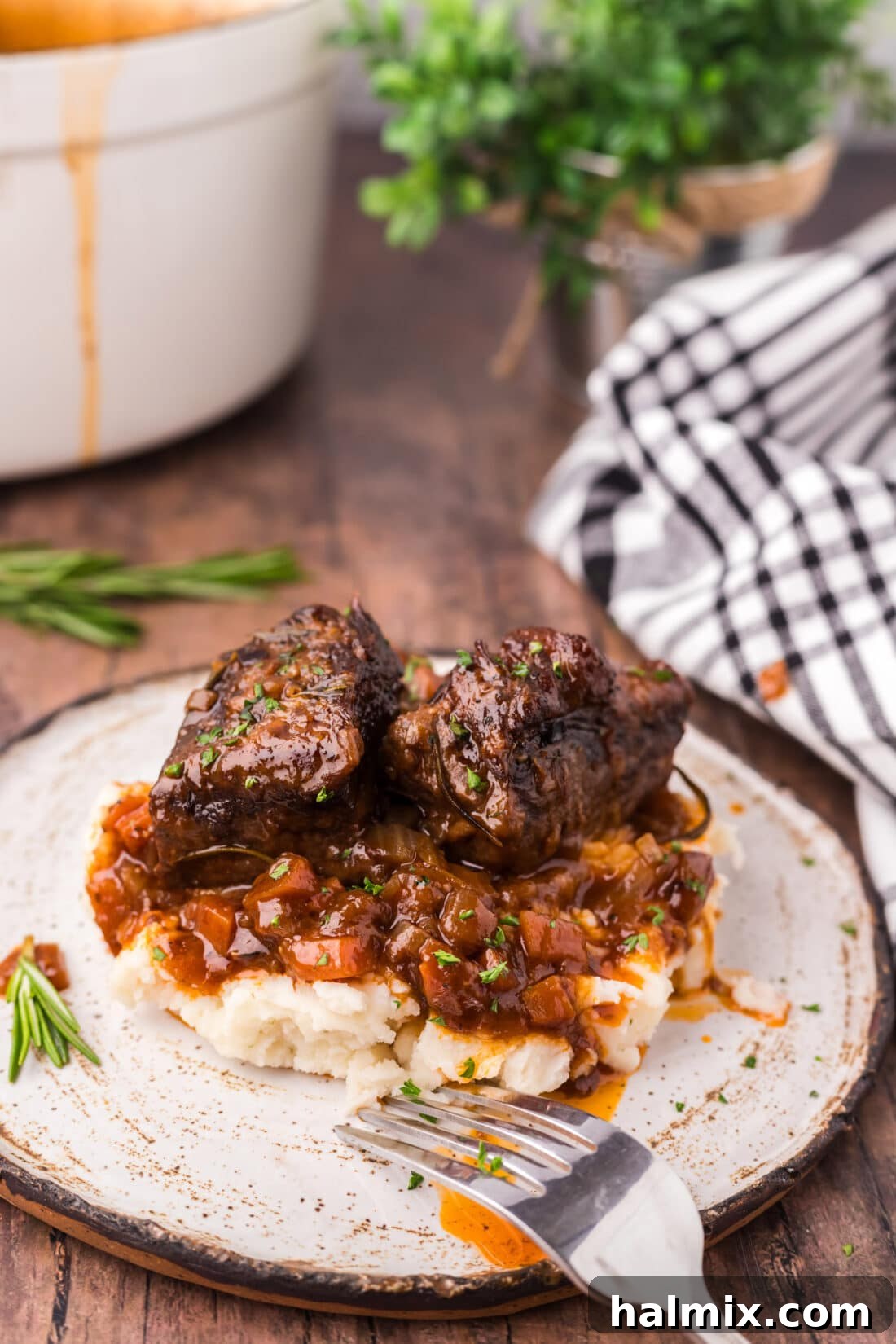 Fall-Off-The-Bone Short Ribs 2 Braised Beef Short Ribs served over creamy mashed potatoes, garnished with fresh herbs.