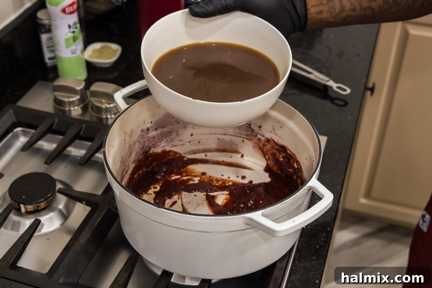Fall-Off-The-Bone Short Ribs 12 Pouring beef broth into the red wine and tomato paste mixture, creating the braising liquid.