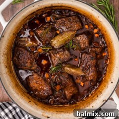 A pot of Braised Beef Short Ribs simmering in rich red wine sauce.