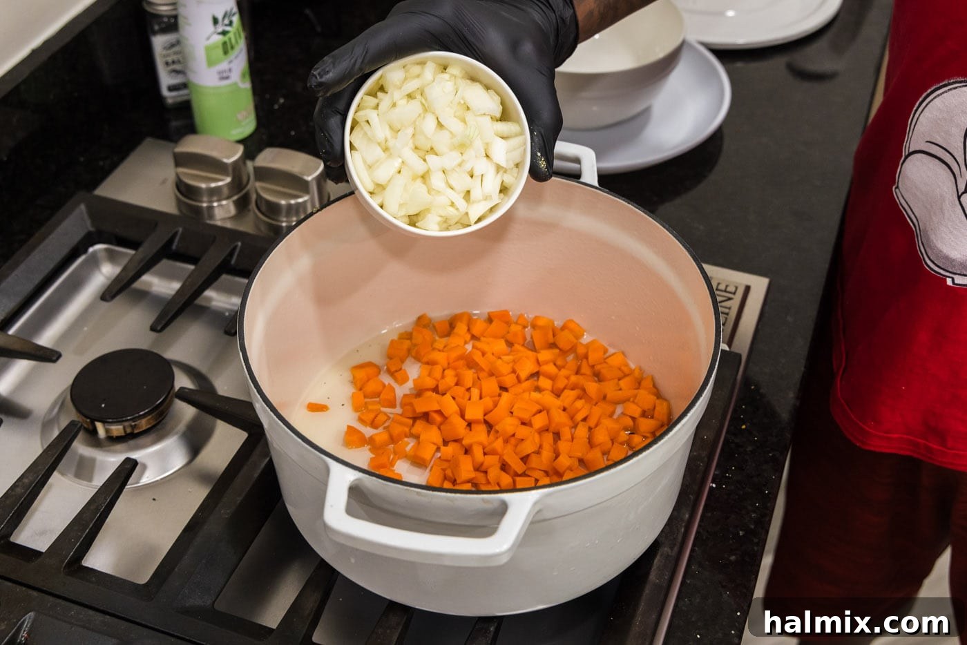 Fall-Off-The-Bone Short Ribs 6 Pouring chopped onion into a Dutch oven with carrots already sautéing.
