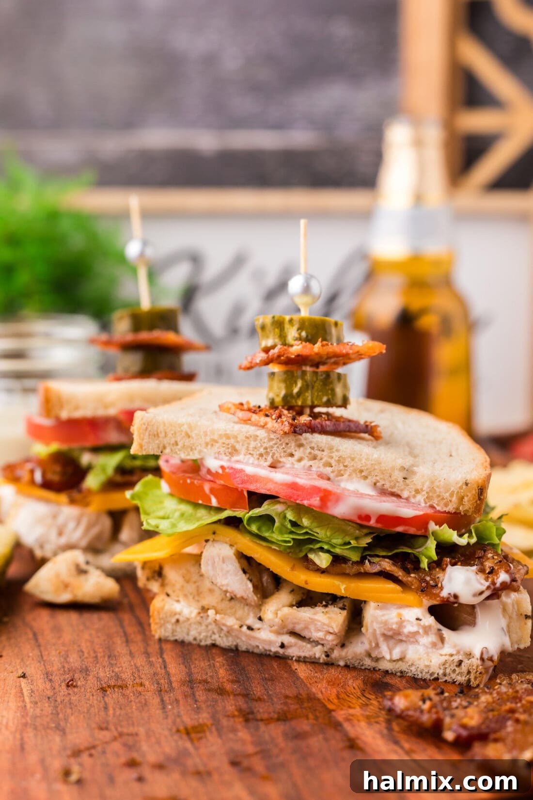 Fried Chicken Ranch Melt 2 Chicken Bacon Ranch Sandwich cut in half, revealing layers of chicken, bacon, cheese, lettuce, and tomato