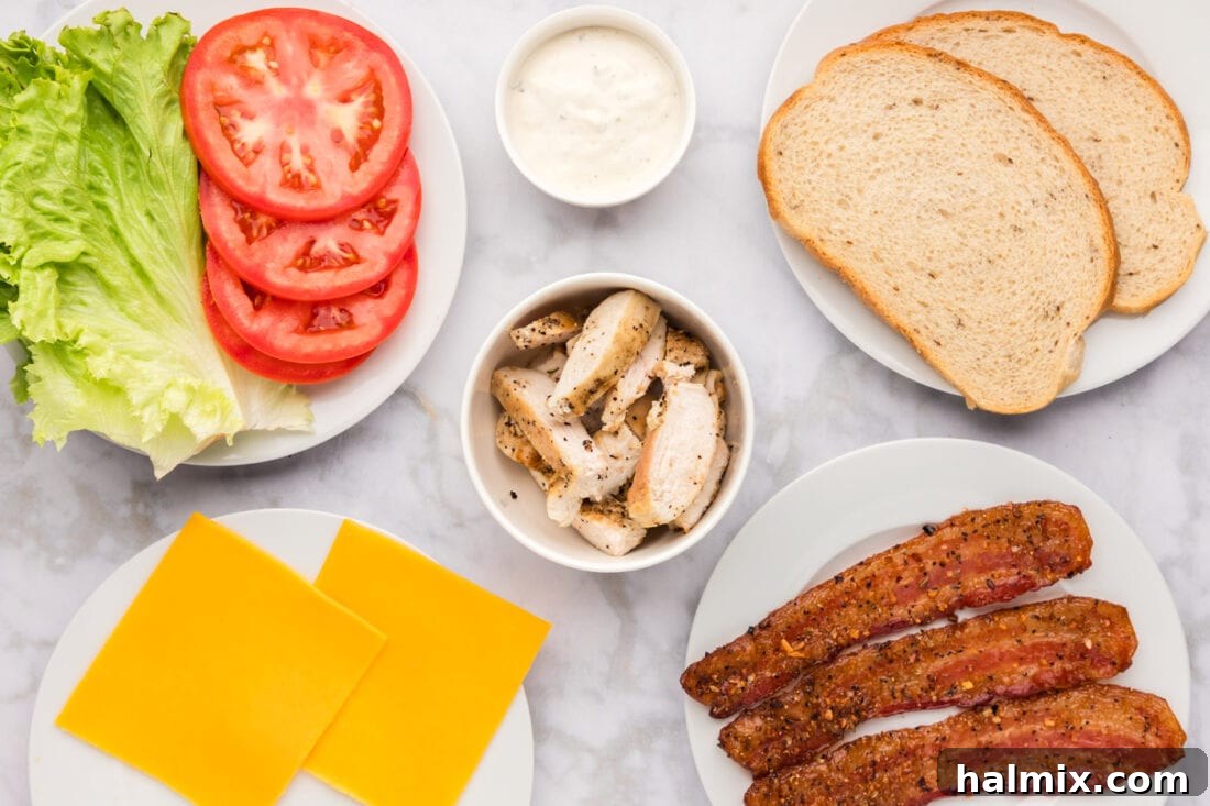 Fried Chicken Ranch Melt 4 Collection of fresh ingredients for a Chicken Bacon Ranch Sandwich, including chicken, bacon, ranch, cheese, lettuce, and tomato