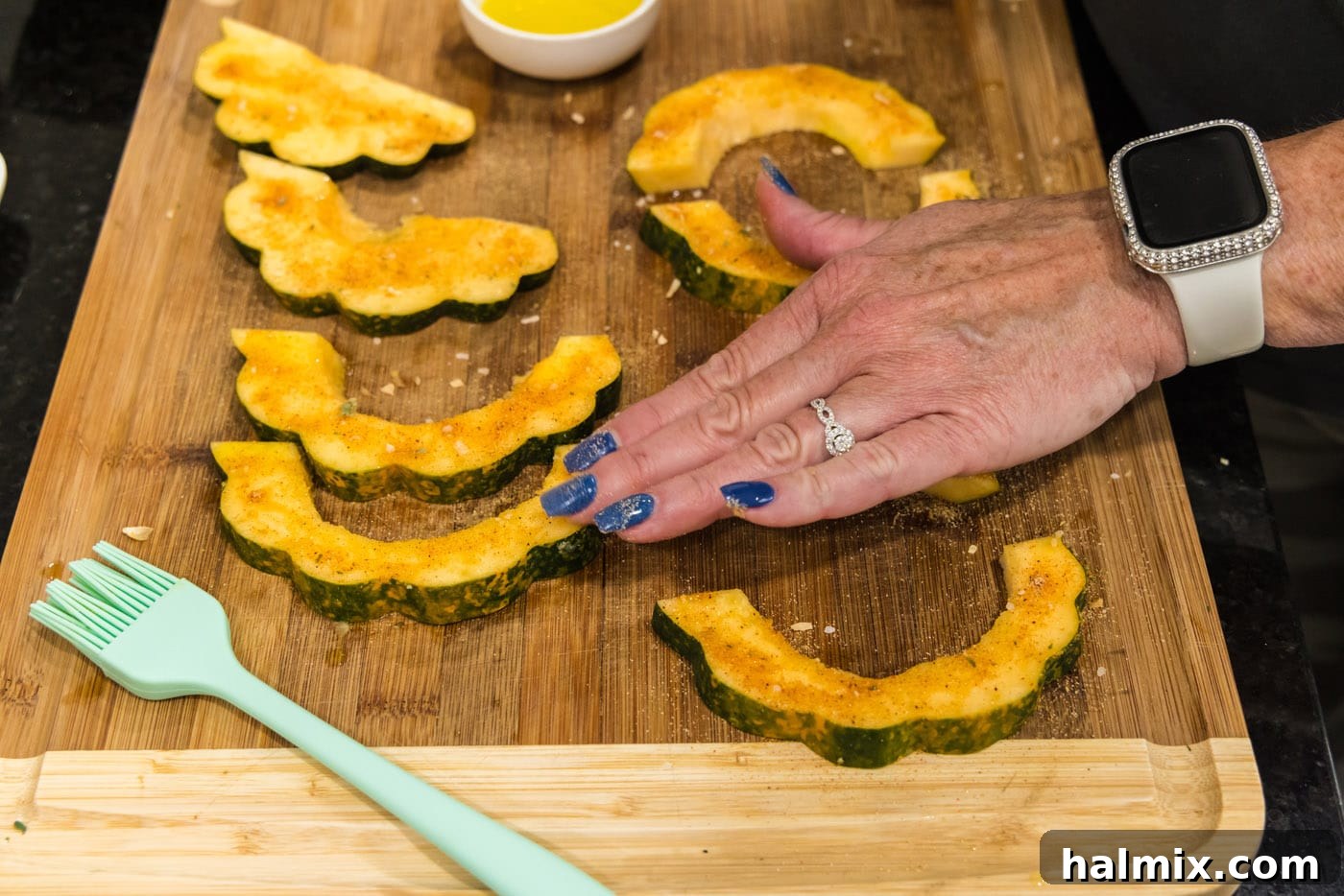 Rubbing all-purpose seasoning blend thoroughly onto acorn squash slices to ensure even coating.