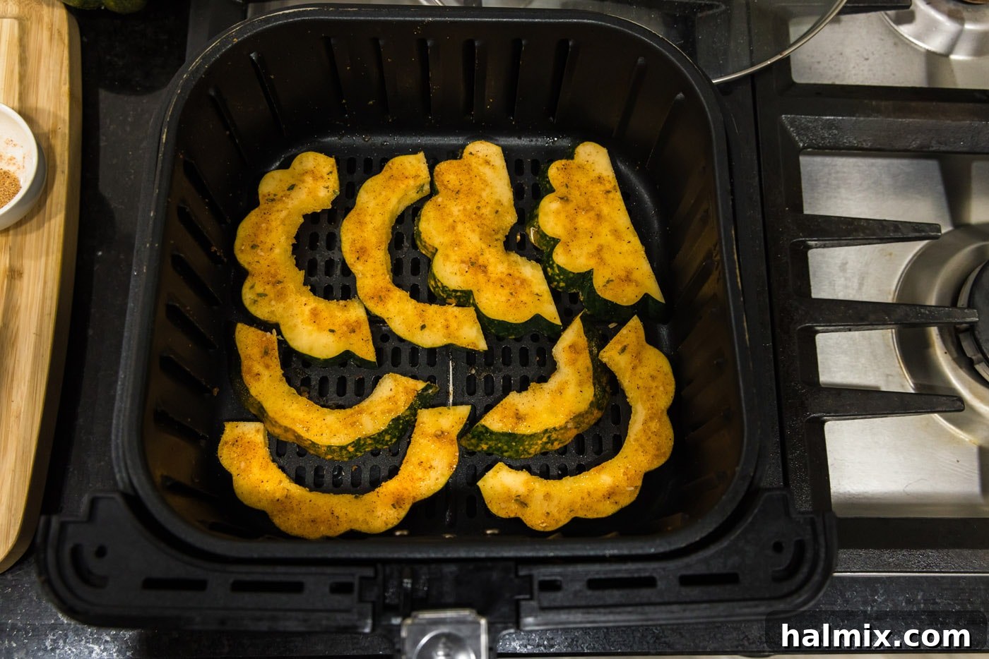 Acorn squash slices meticulously arranged in a single layer within the air fryer basket for optimal cooking.