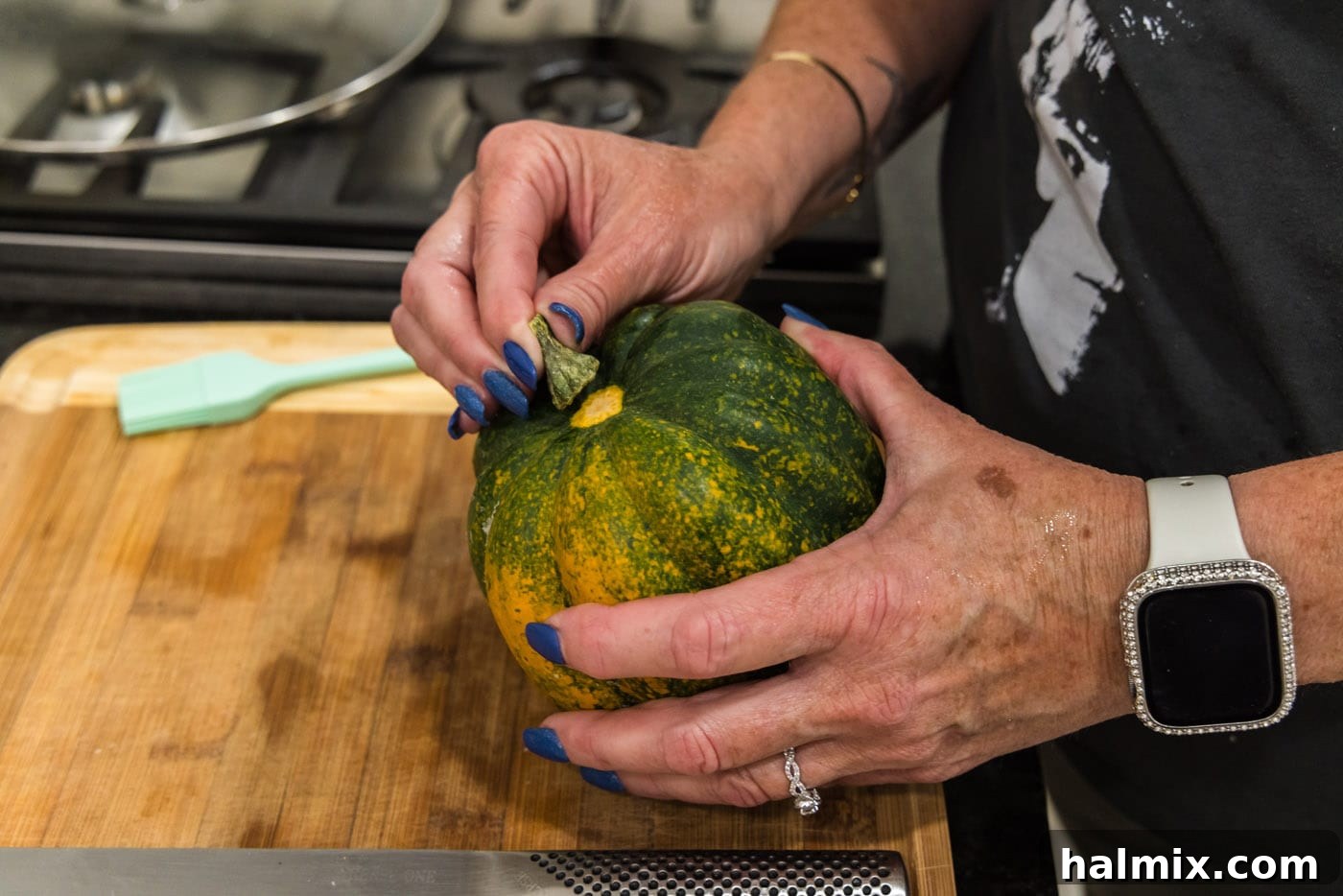 Removing the stem from an acorn squash before slicing to ensure a stable cutting surface.