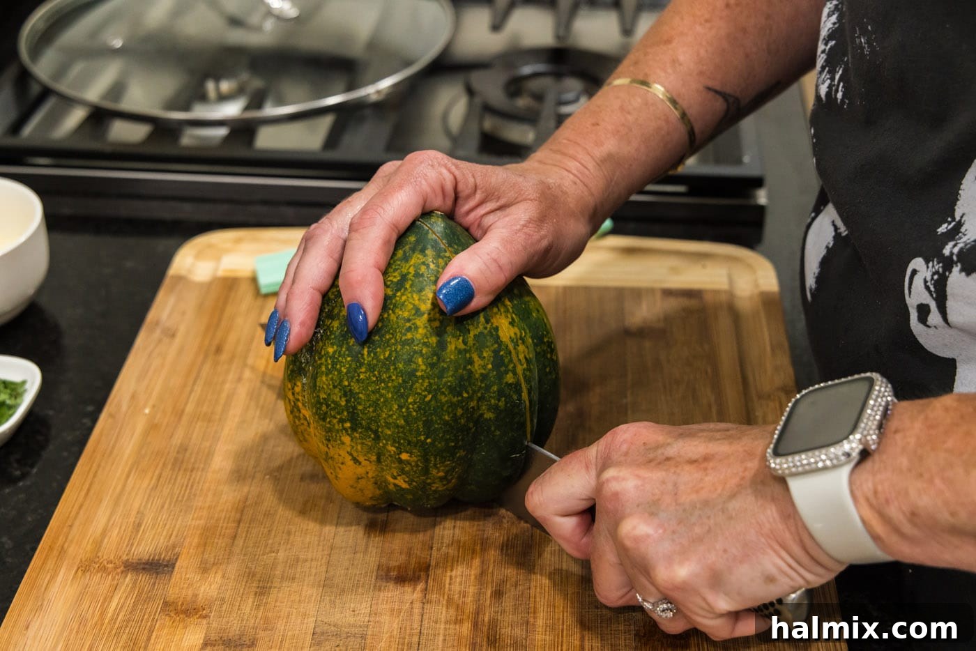 Slicing an acorn squash in half to reveal its inner seeds and pulp.