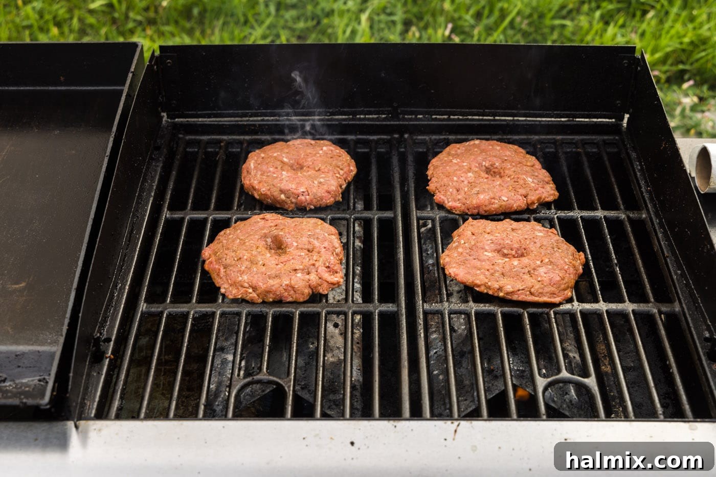 burger patties cooking on a grill grate, showing even cooking.