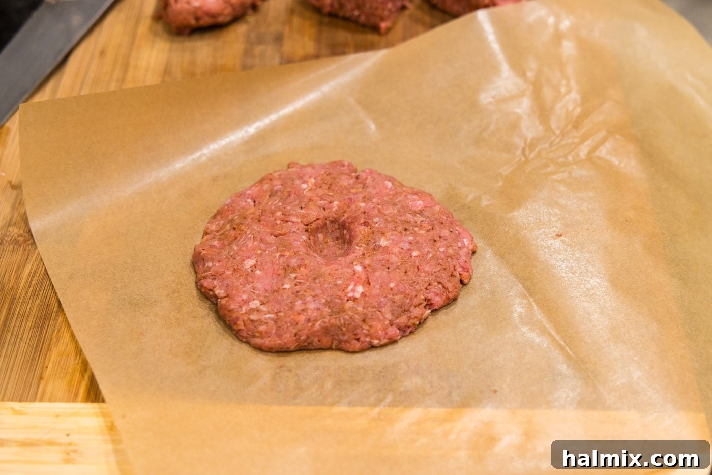 creating an indent in burger patty, showing the technique for even cooking.