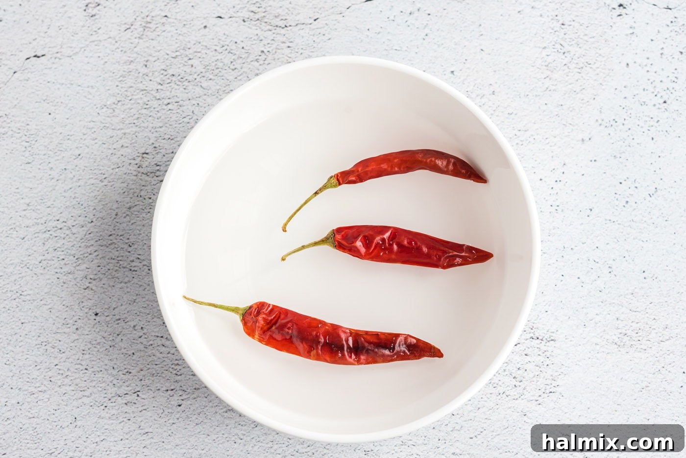 Dried red chiles soaking in a bowl of hot water.