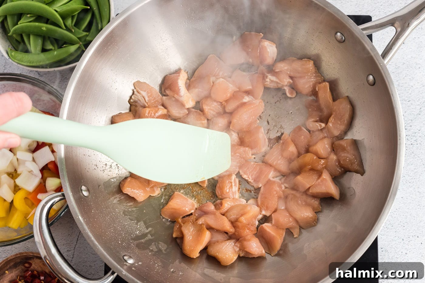 Chicken pieces searing in a hot wok, browning nicely.
