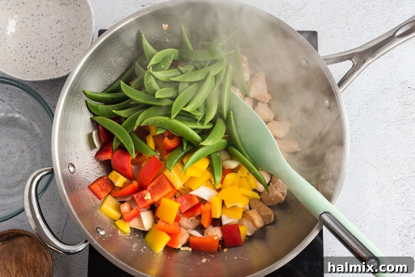 Mixed vegetables and chicken stir-frying together in a wok.