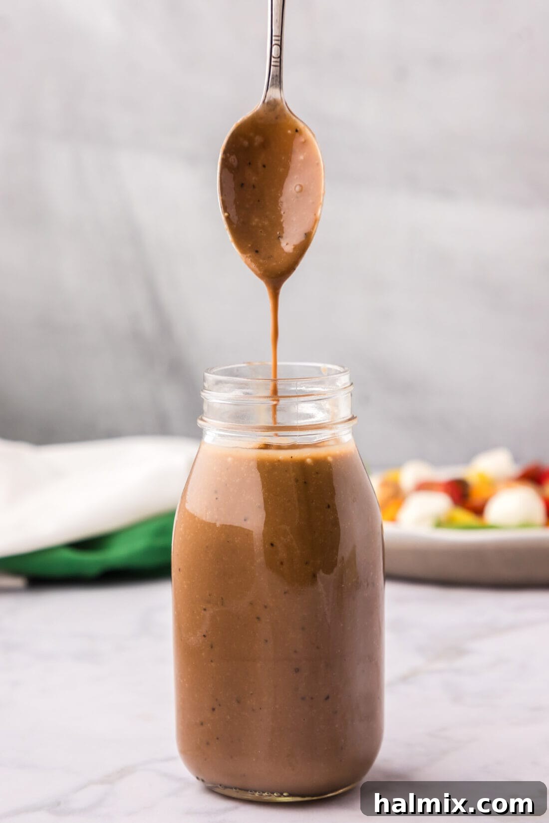 Sweet-Tart Balsamic Dressing 3 Balsamic Vinaigrette drizzling off a spoon into a jar, showcasing its smooth texture