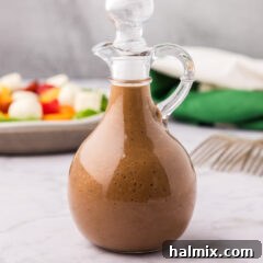 Close up photo of a cruet filled with Balsamic Vinaigrette, showcasing its beautiful color and texture.