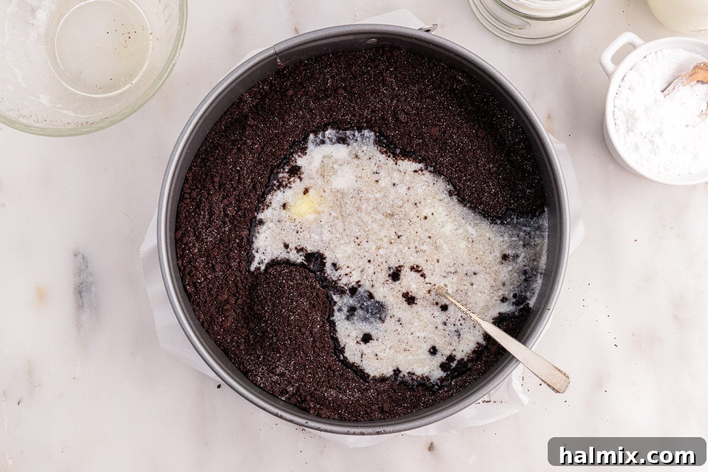 mixing graham cracker crumbs with melted butter into a sandy mixture