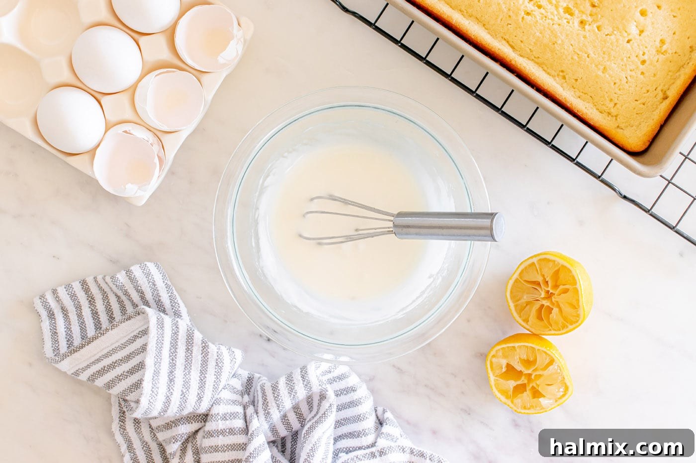 Lemon glaze in a bowl with a whisk, showing its smooth and pourable consistency.