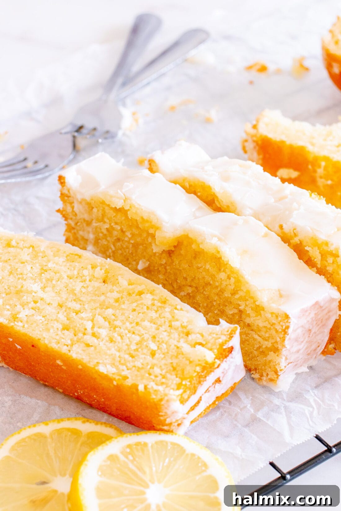 Multiple slices of Lemon Pound Cake arranged on parchment paper, ready to be enjoyed.