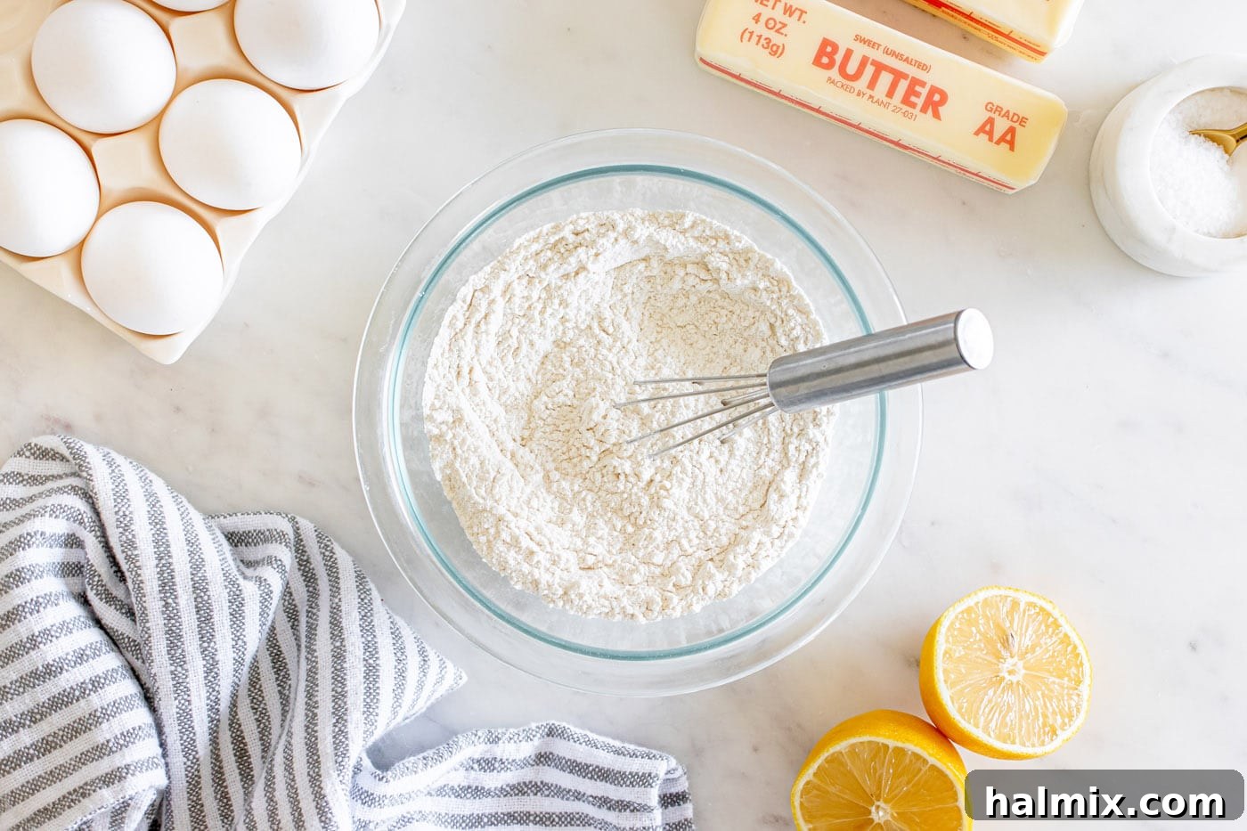 Dry ingredients for lemon pound cake whisked together in a bowl, showing flour, baking powder, salt, and lemon zest.