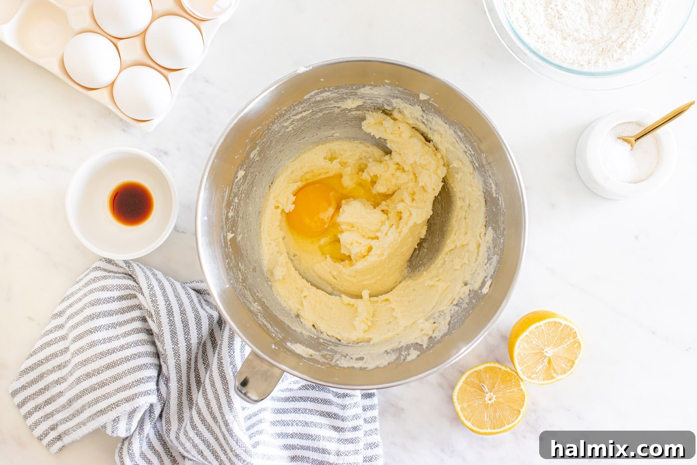 Adding eggs one by one to the beaten butter and sugar mixture in a stand mixer.