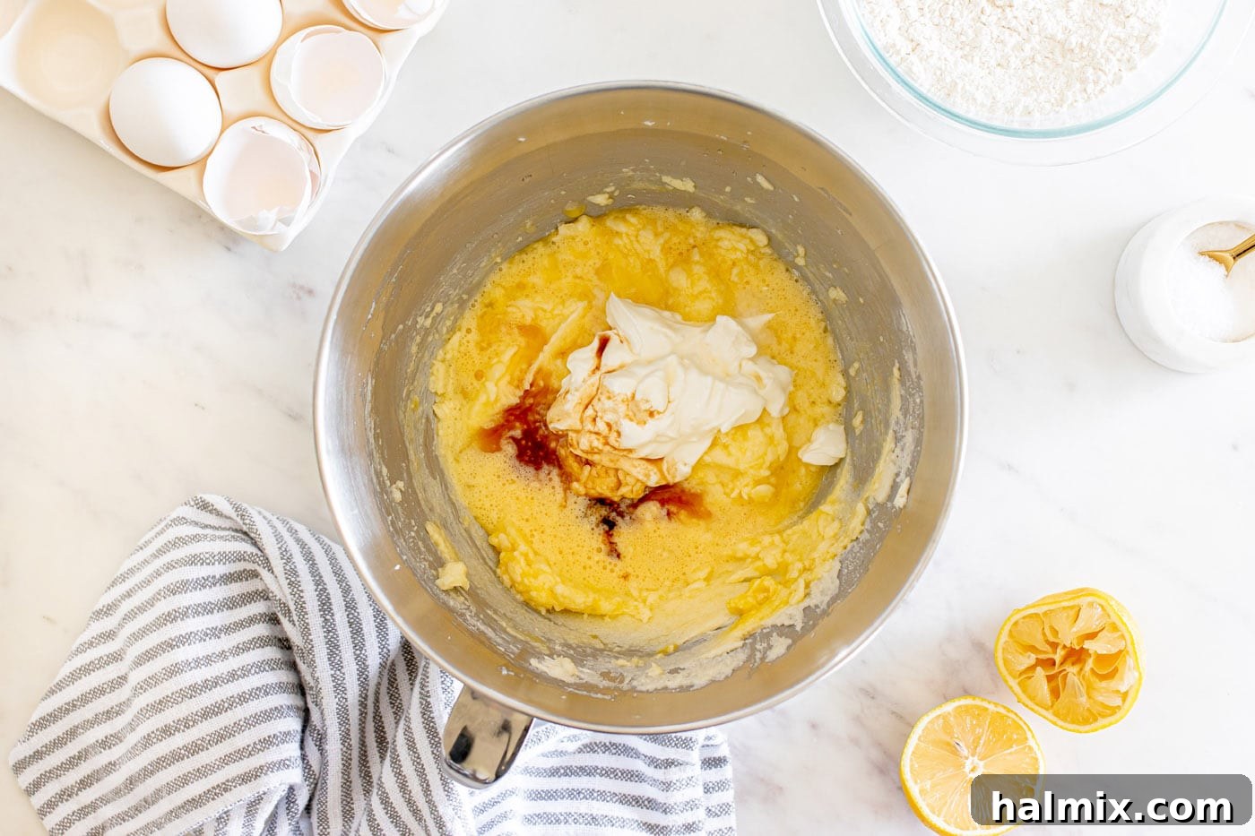 Adding sour cream and vanilla extract to the butter and egg mixture in a mixing bowl.