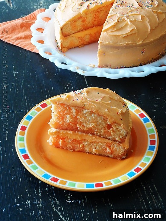 A vibrant slice of orange poke cake, glistening with gelatin, resting on an orange plate, ready to be enjoyed.