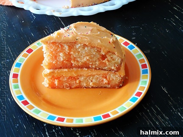A stunning side profile of the Orange Poke Cake, revealing its beautiful layers and generously applied frosting.