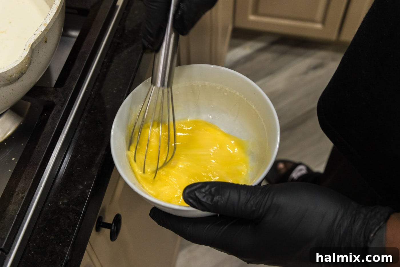 Beaten eggs in a medium bowl, ready for tempering into the sauce.