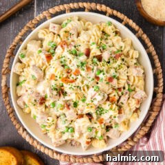 An overhead shot of a bowl of Turkey Carbonara, beautifully arranged with creamy pasta, cubed turkey, and crisp bacon, garnished with fresh herbs.