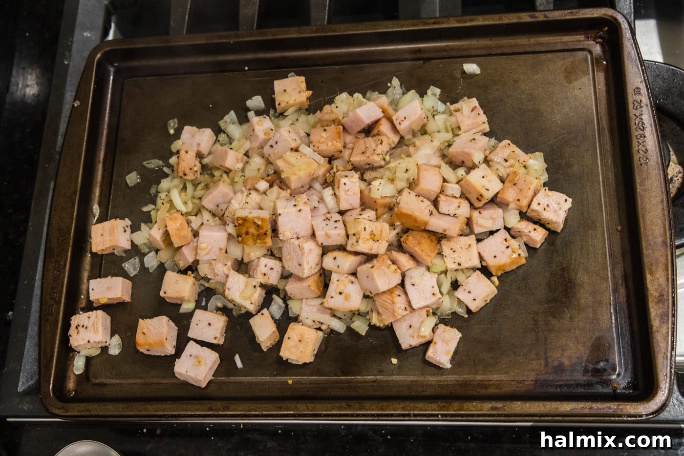 The cooked turkey, onion, and garlic mixture evenly spread out on a baking sheet, ready to be set aside.
